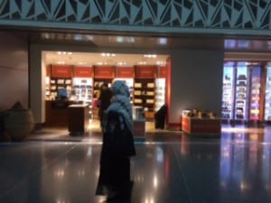 Qatari woman and shop. They blend into the scenery compared to the resplendent men